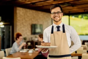 Male waiter in an apron serving food in a Dubai hotel restaurant setting